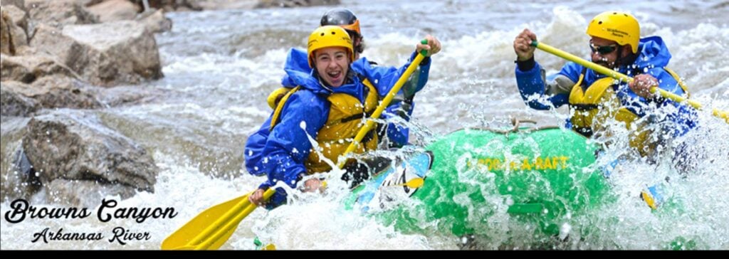 three people paddle a green raft with yellow paddles