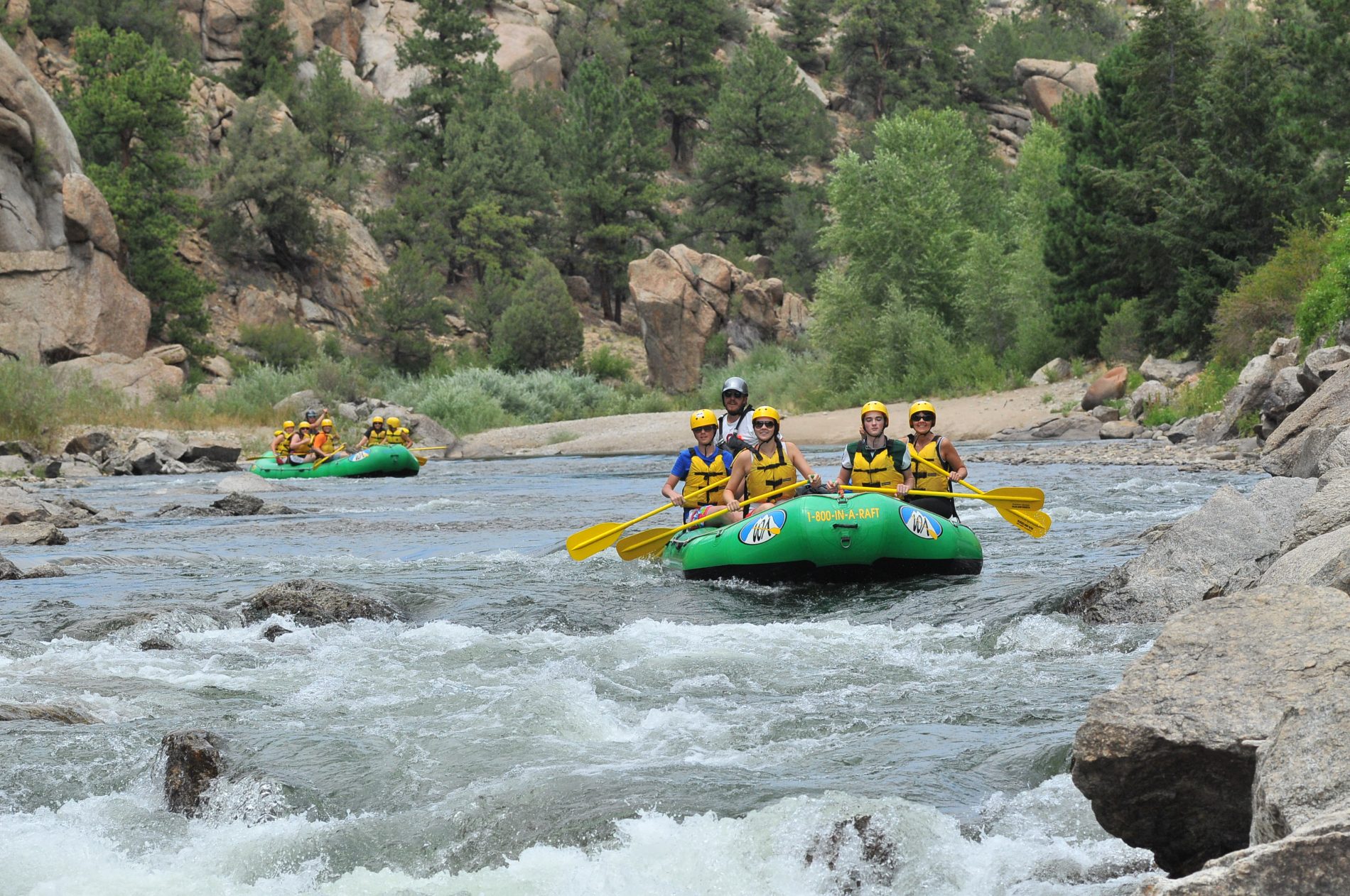 two green rafts with people on a scenic river