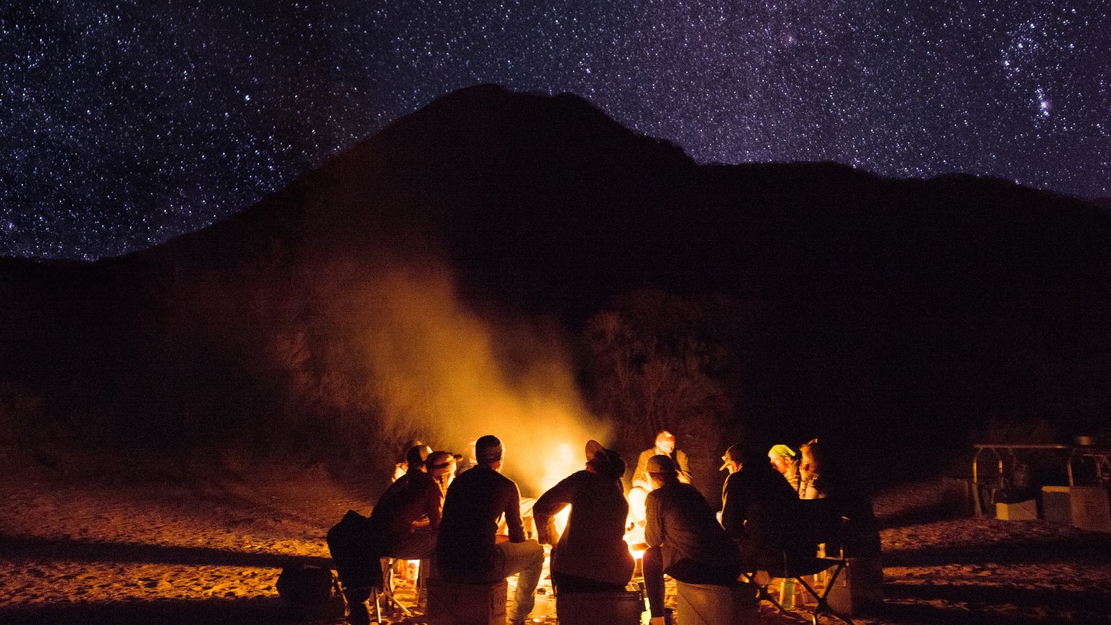 People sit around a fire under a starry sky in colorado