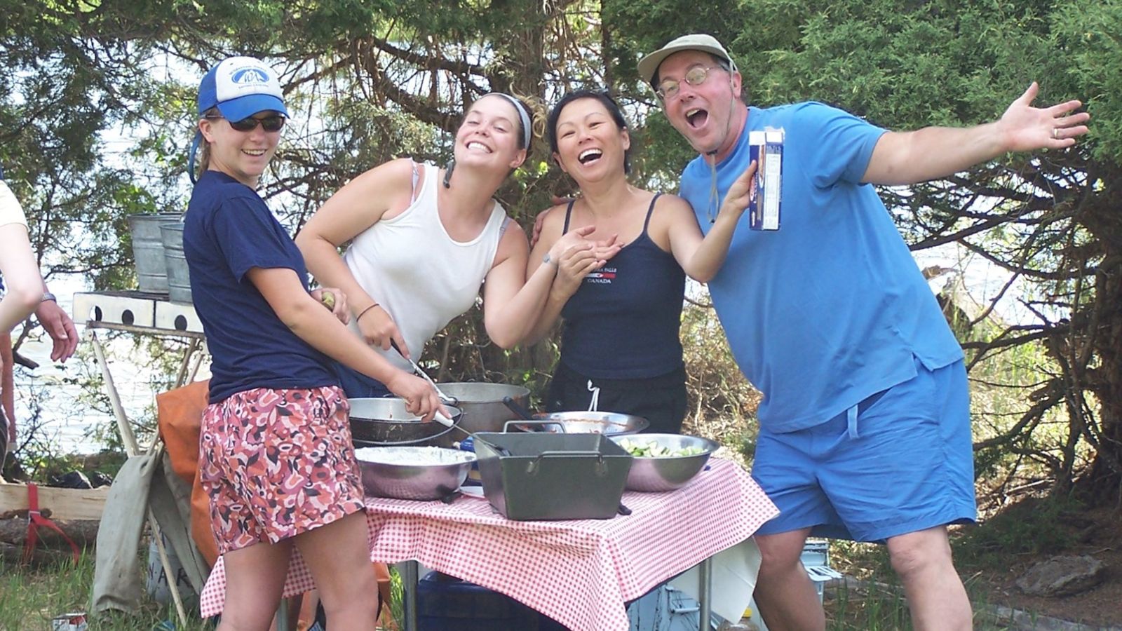 River guides smile as they prepare a meal on the riverbank