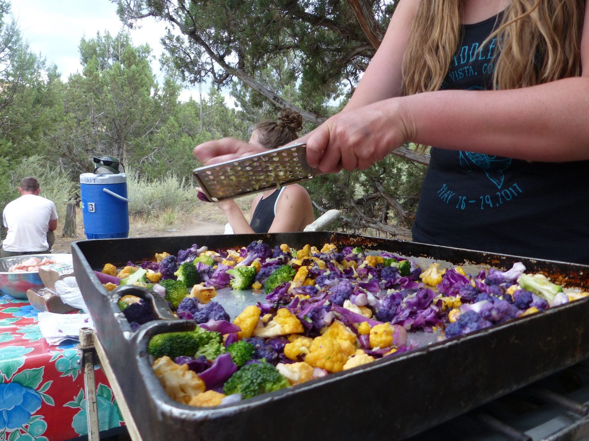 A chef cooks cauliflower, broccoli and more near a river.