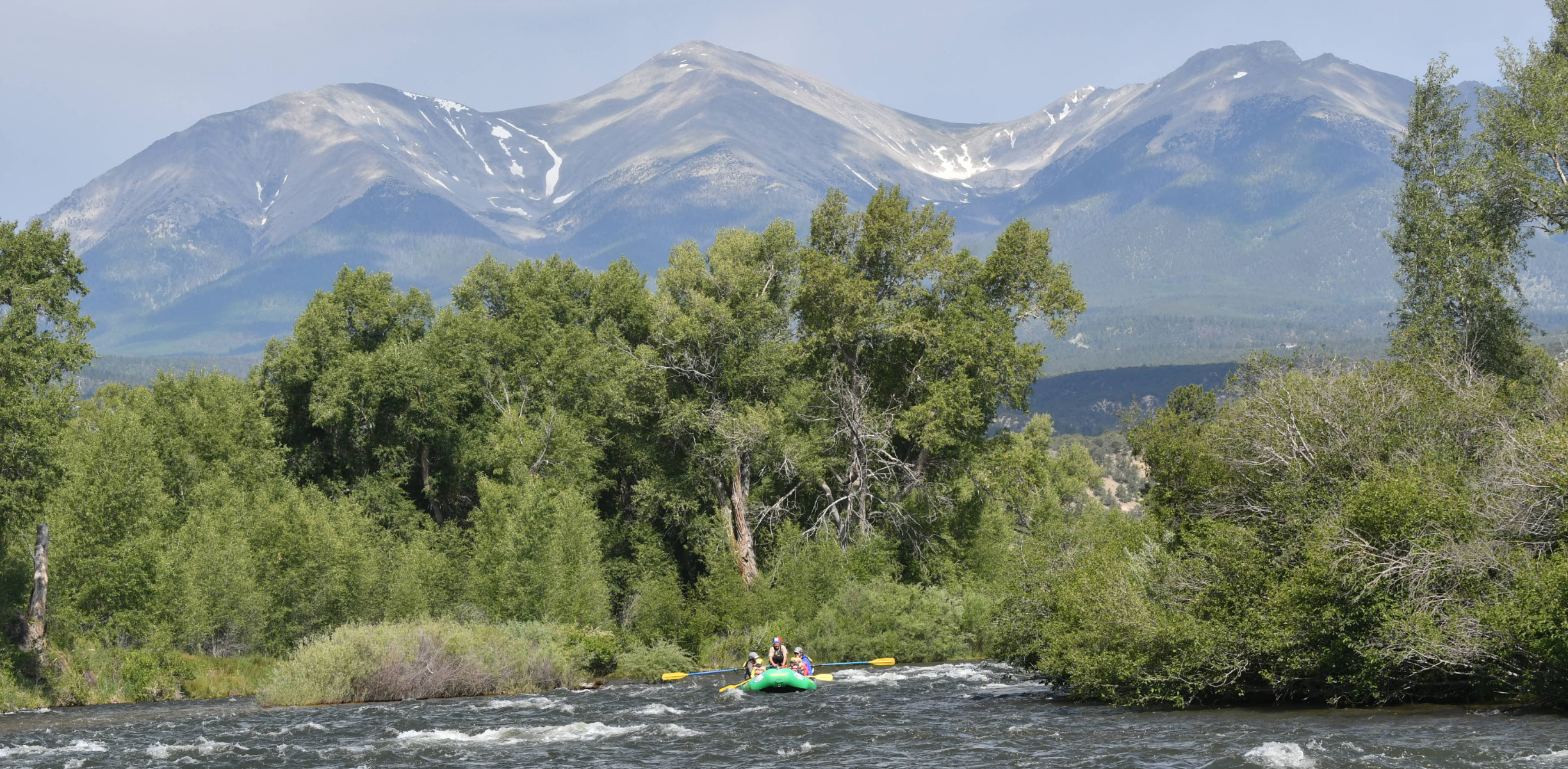 A raft floats down a scenic and calm river section in Colorado