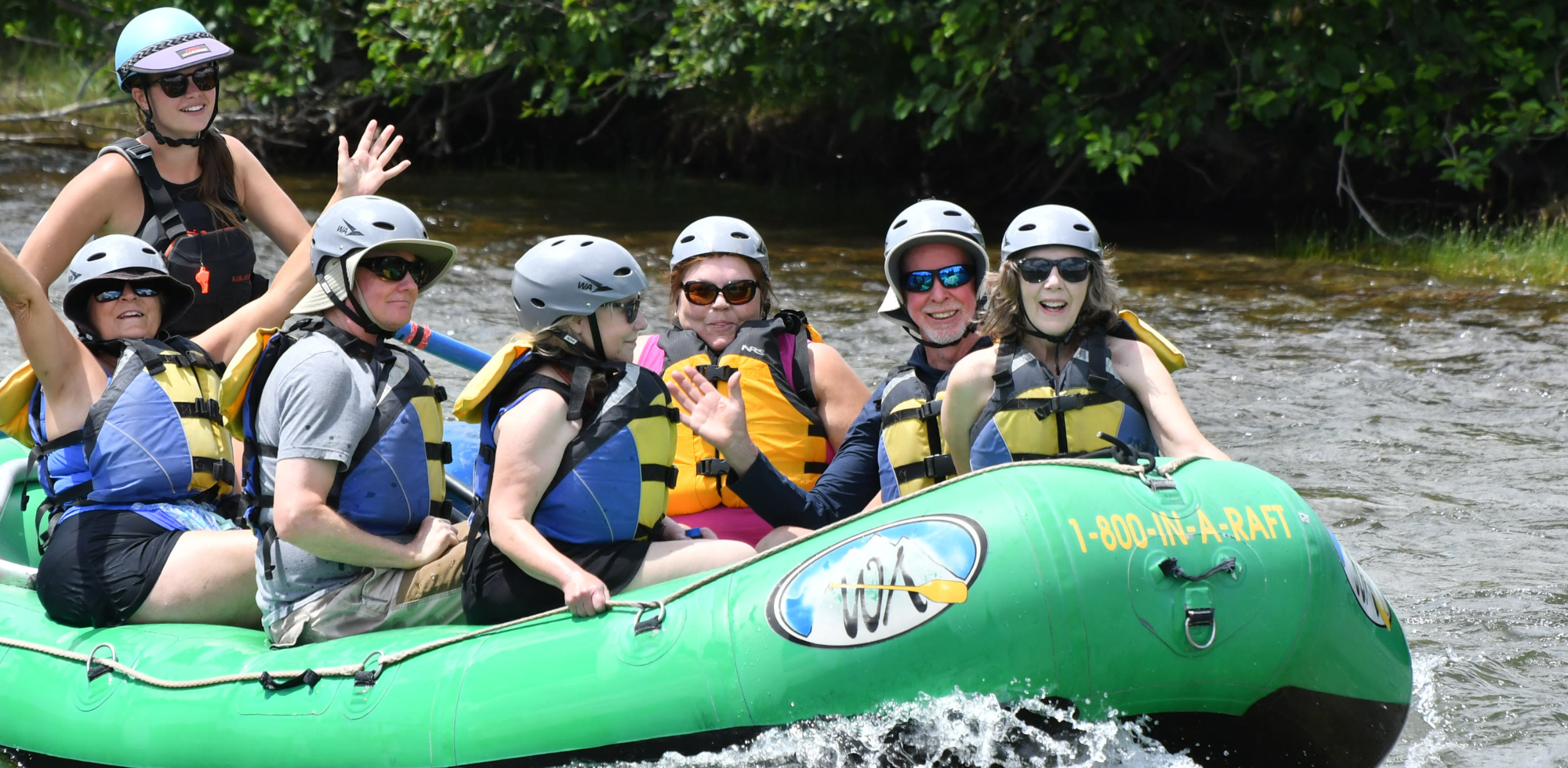 A group of people on a guided river trip on a river in a green boat