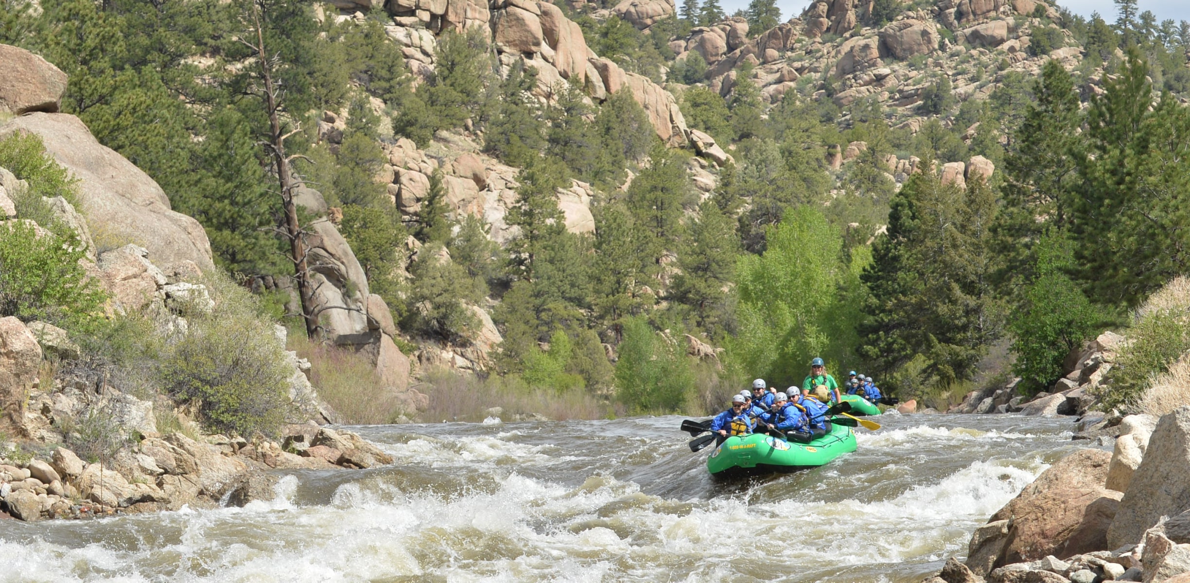 A group of rafters preparing to navigate white water rapids in Browns Canyon, Colorado, surrounded by rocky canyon walls and scenic wilderness.