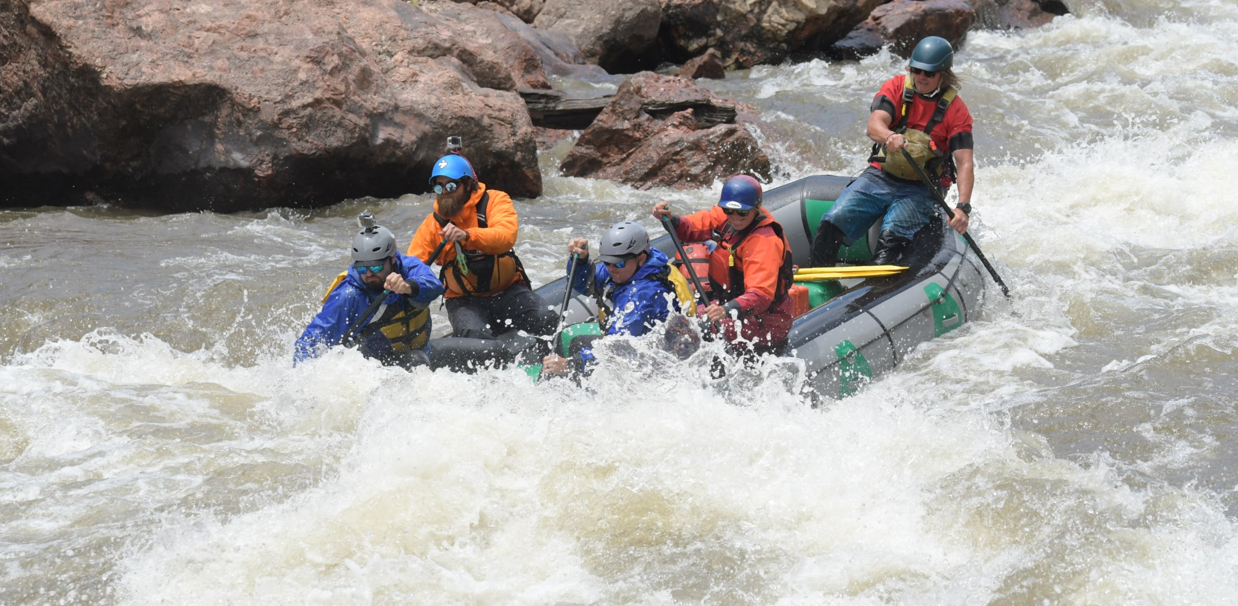 People in a raft paddling through whitewater