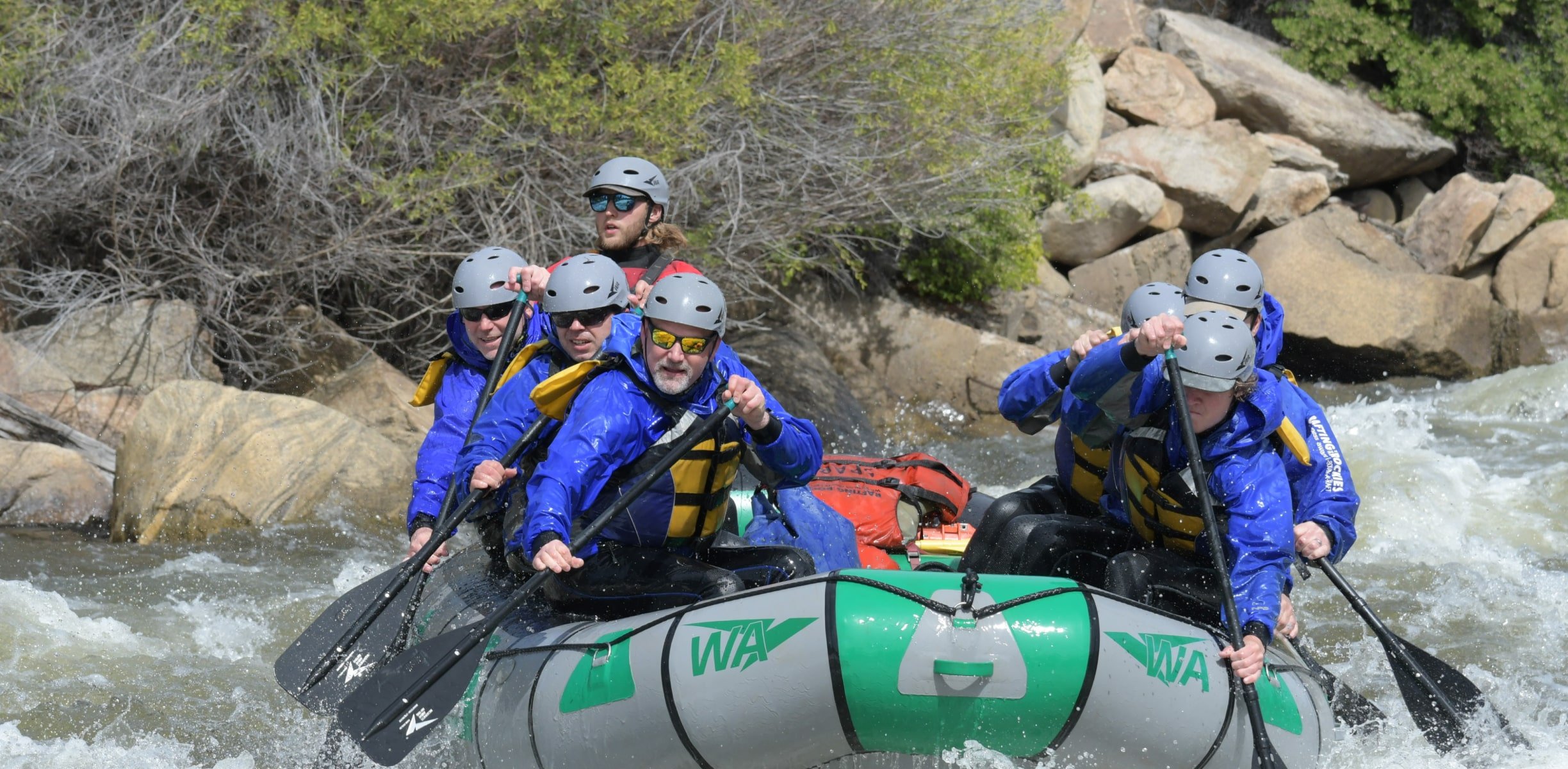 A group paddling through whitewater in a raft