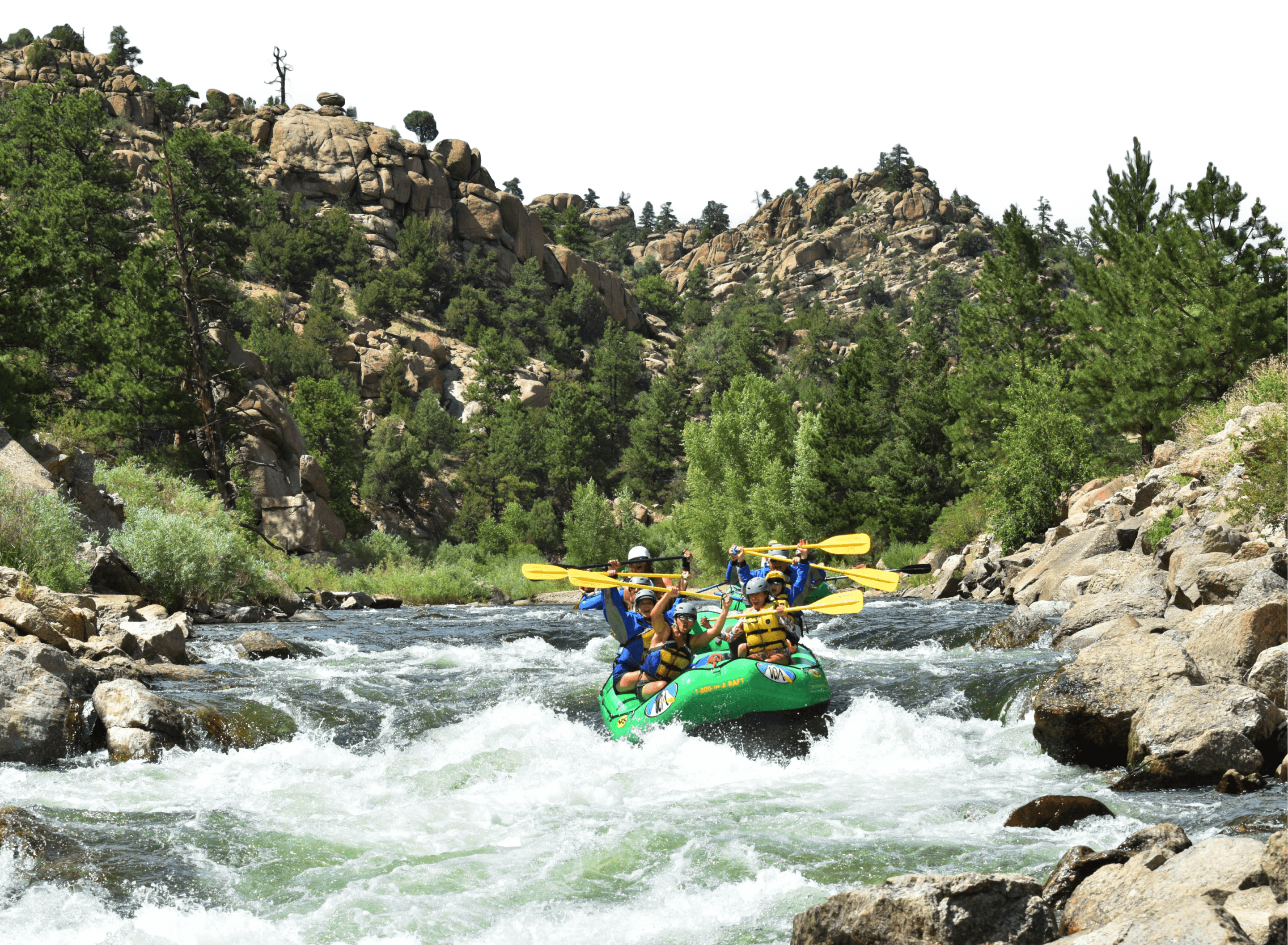 People in a green raft on the river holding their oars in the air