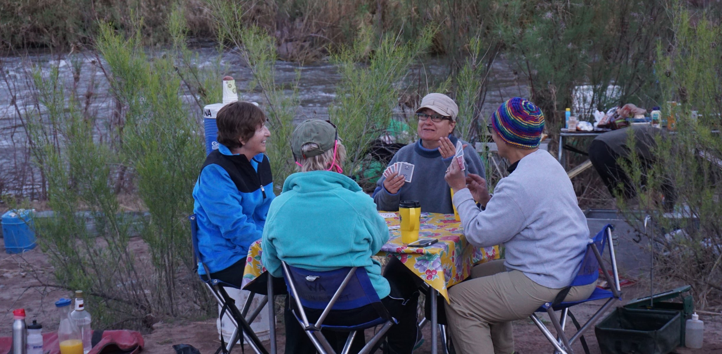 A group of people playing cards while camping riverside in Arizona