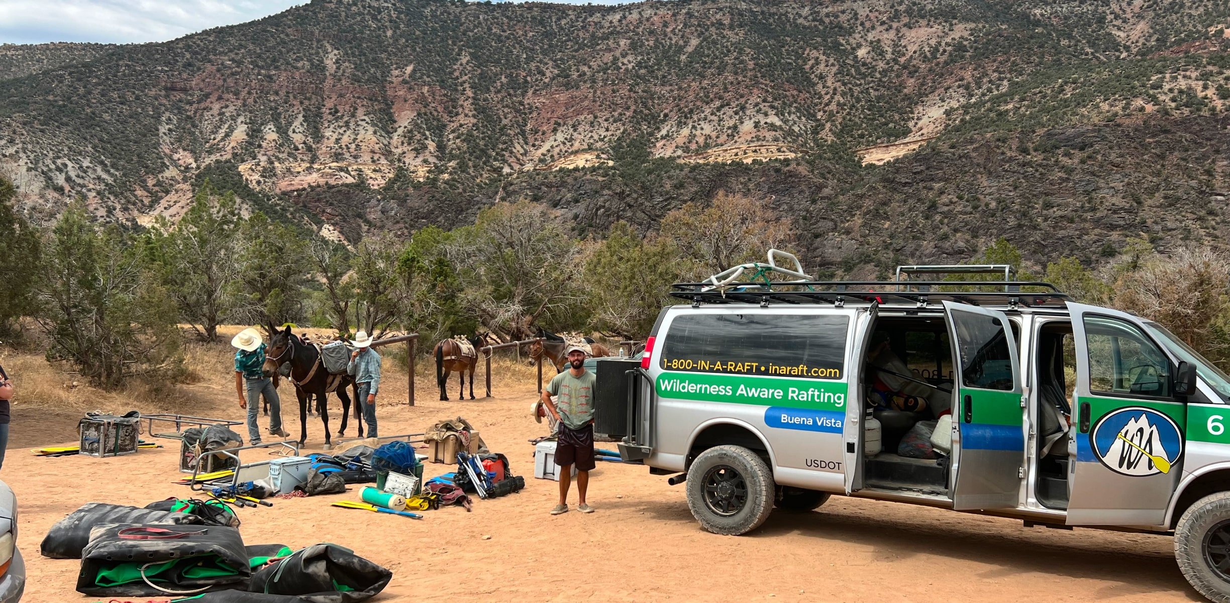 A man outside standing outside a van unloading gear and packing horses