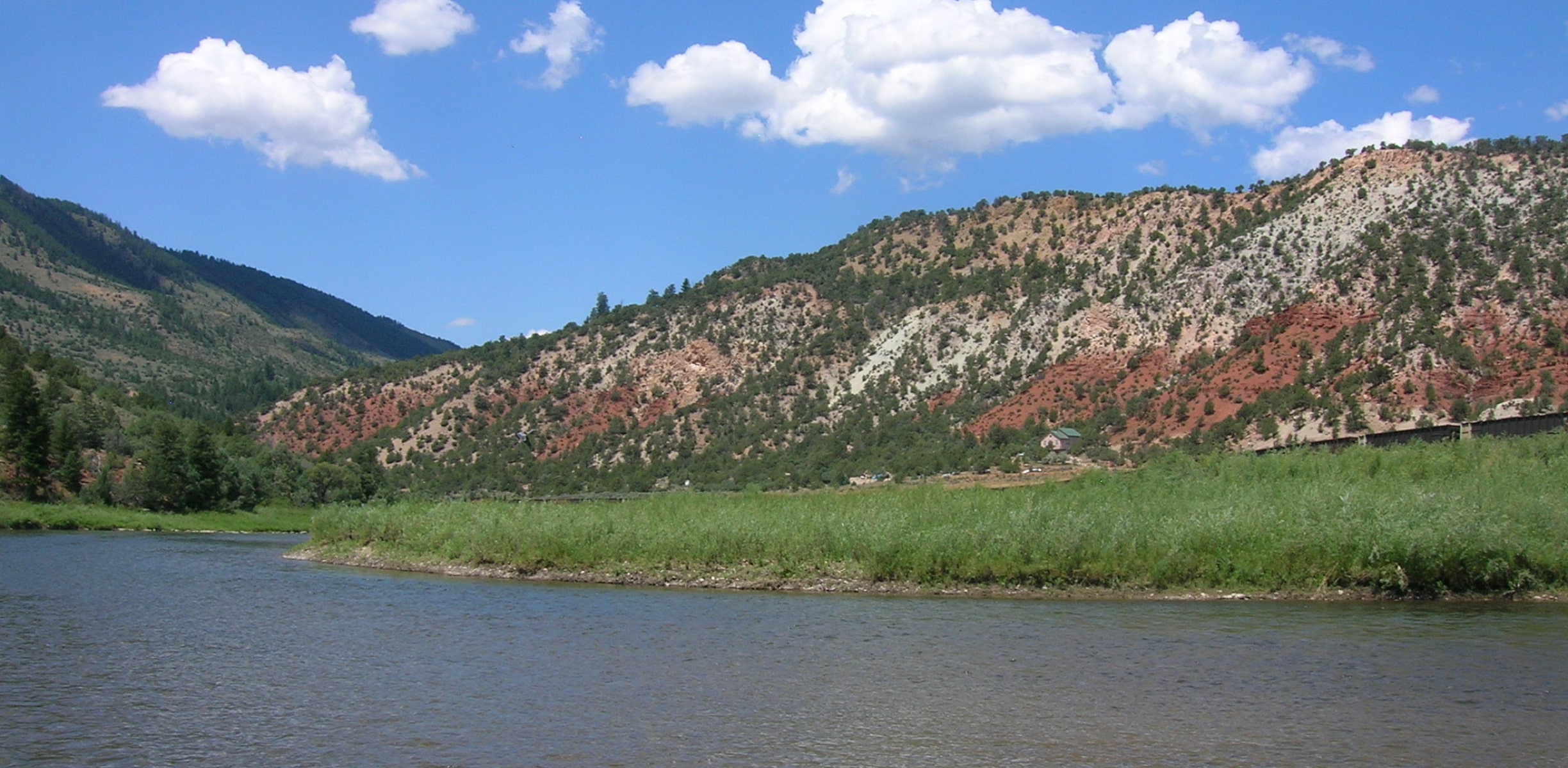 A scenic river in colorado with mountains on either side and blue skies