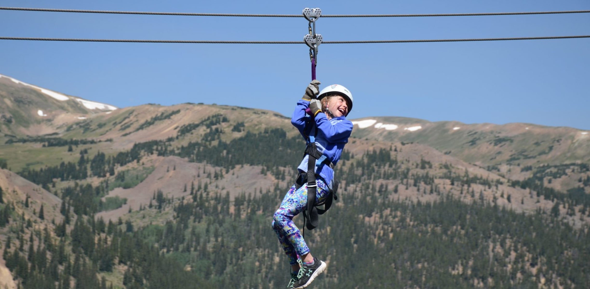 A young child ziplining with a big smile