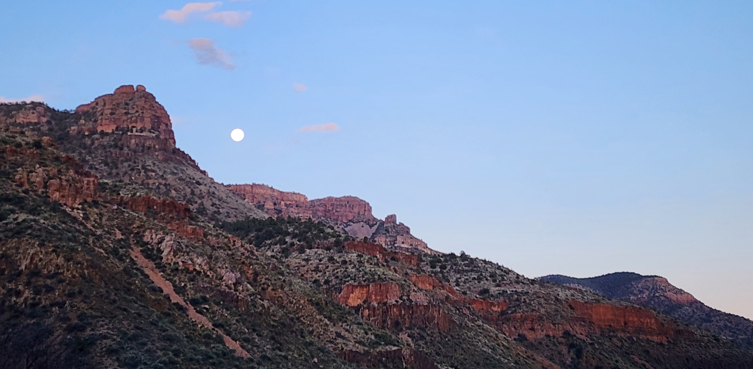 A scenic shot of the Salt River Wilderness in Arizona with the moon over a mountain