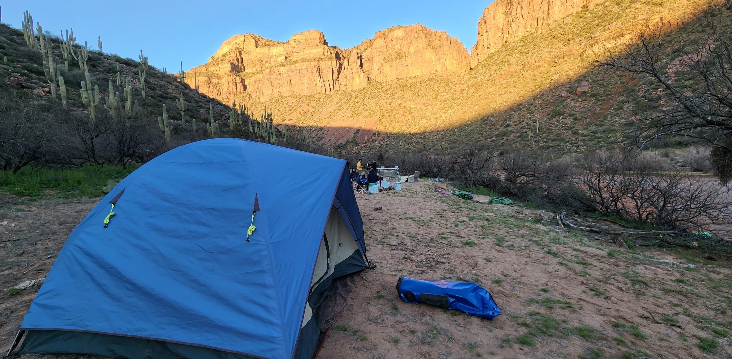 A tent tucked under some canyons next to a river in arizona