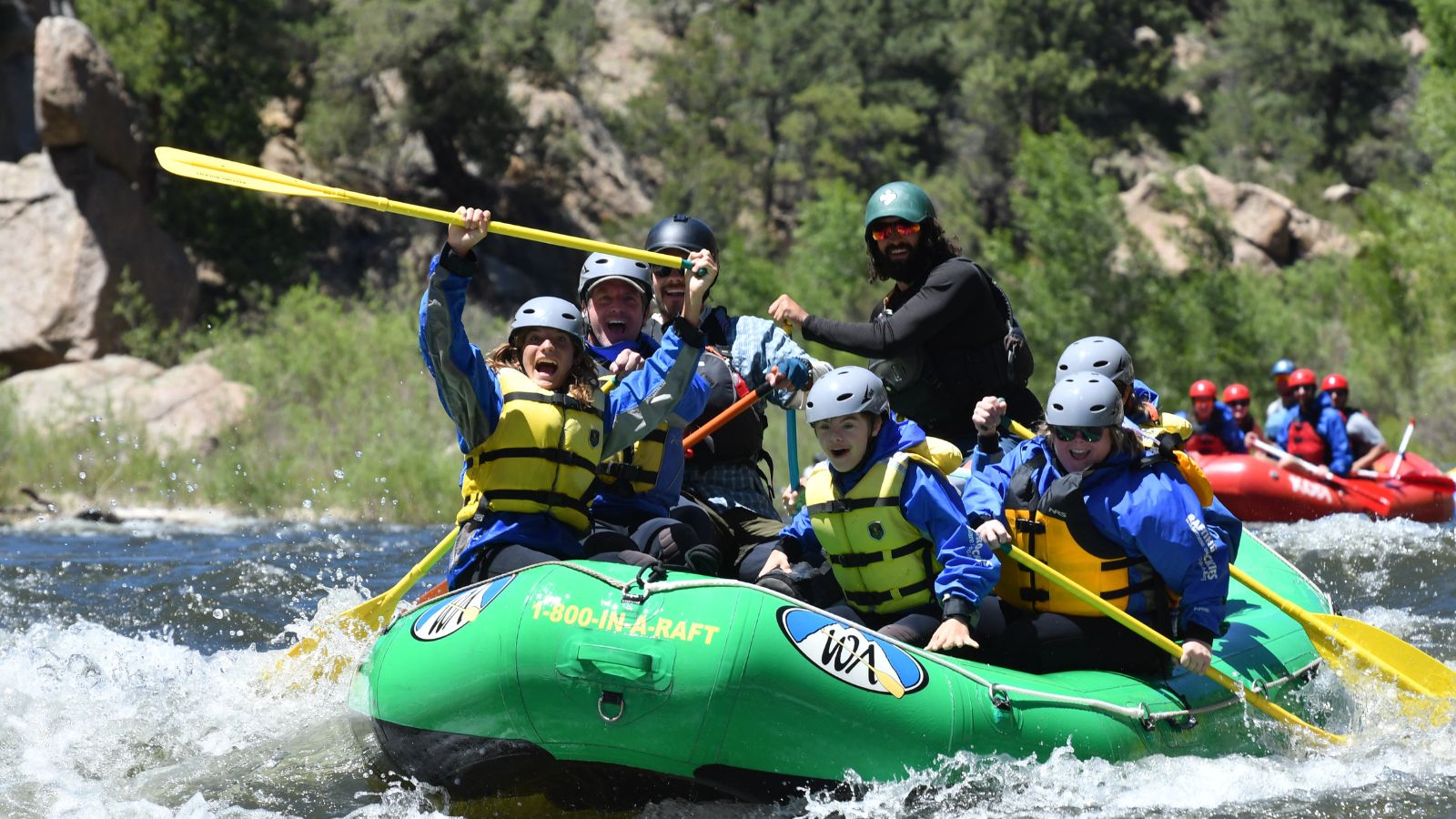 People in a green boat rafting on a river