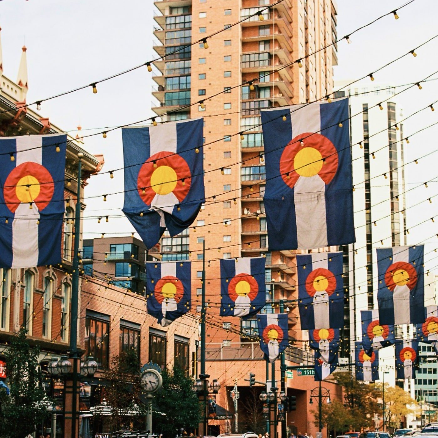 A street in denver with Colorado flags, lights and tall buildings