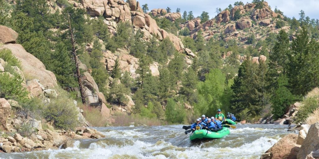 Groups of rafts entering rapids during a Browns Canyon river rafting trip, surrounded by scenic canyon boulders.