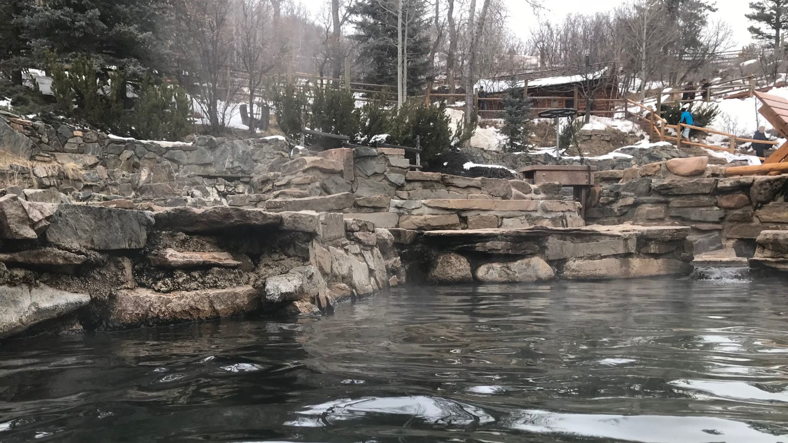 a hot spring pool surrounded by rocks in the winter