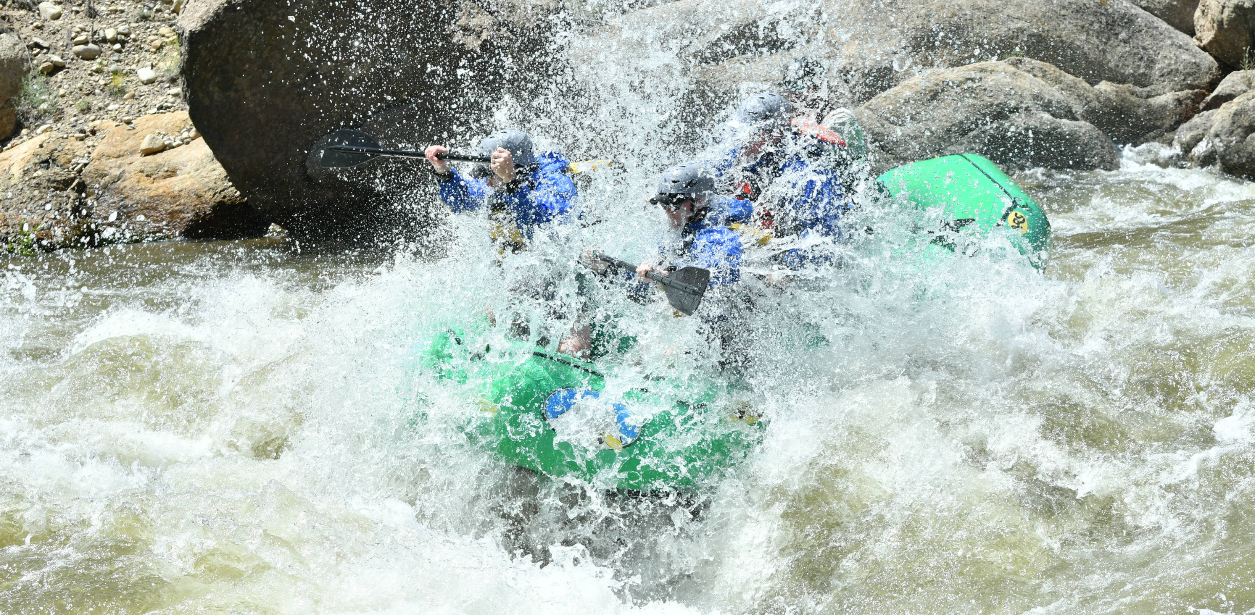 People in a boat on the arkansas river raft through extreme white water